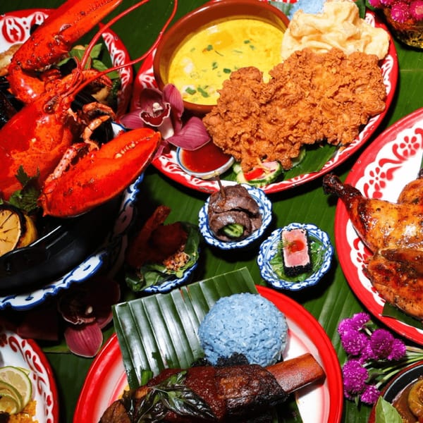 A vibrant Thai feast with lobster, fried chicken, blue rice, and various dishes on banana leaves.